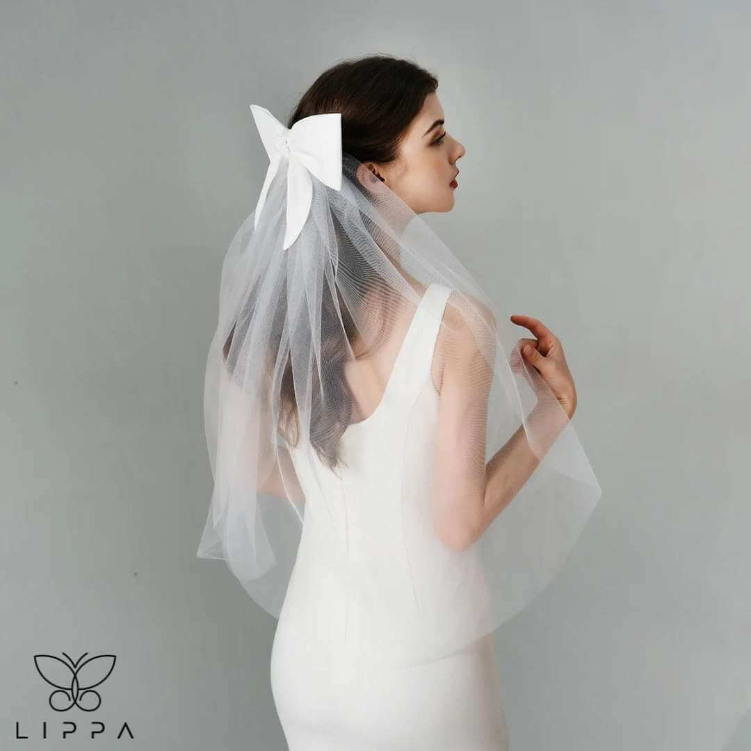 Ivory satin bridal bow veil headdress with a delicate tulle veil, perfect for weddings and special occasions. Lightweight and elegant wedding hair accessory