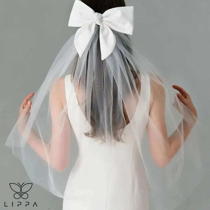 Ivory satin bridal bow veil headdress with a delicate tulle veil, perfect for weddings and special occasions. Lightweight and elegant wedding hair accessory