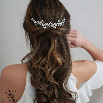 Back view of a bride wearing an elegant handmade pearl and crystal wedding hair vine with intricate flower and leaf designs, styled with soft curls