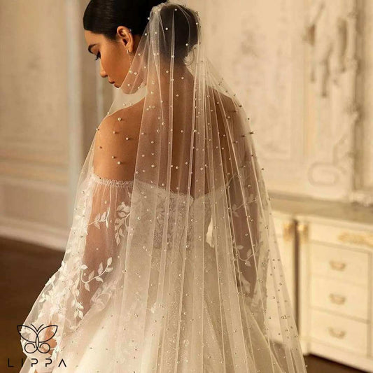 Elegant cathedral-length bridal veil made of soft tulle with delicate pearl embellishments, featuring a 1-tier design and attached comb for secure wear. Perfect wedding accessory